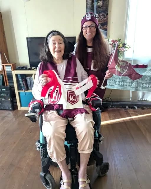 A Parcare participant and her support worker in Maroons colours on game day